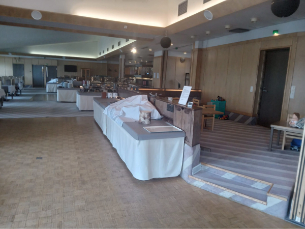 photo of dining hall. The floor is flat, except for the entrance to the kitchens which has two steps leading up to it and a children's play area